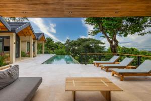 an outdoor patio with a pool and lounge chairs at Villa Bahia Oceanview Designer Retreat Malpais in Mal País