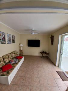 ein Wohnzimmer mit Couch und Flachbildfernseher in der Unterkunft Sobrado aconchegante com Piscina Ar Condicionado 3 quartos a 150 metros do mar no Brejatuba in Guaratuba