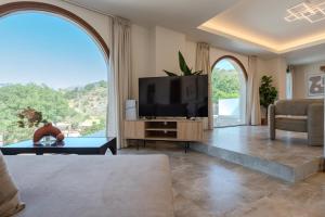 a living room with a tv and a large window at Casa Karinea - Serene Stone House Retreat in Áyios Vasílios