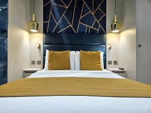 a bedroom with a large bed with yellow pillows at NOX Chelsea in London