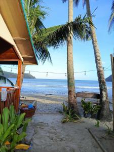 Una playa con dos palmeras y el océano. en UHHA Inn, en Locaroc 34 fotos más