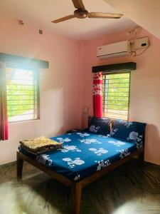 - une chambre avec un lit bleu dans une pièce dotée de fenêtres dans l'établissement Sneh Beach Homestay - Wayangani Vengurla, à Vengurla
