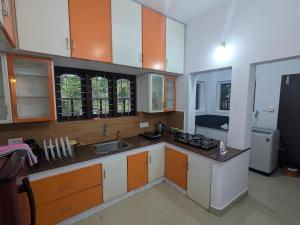 a kitchen with orange and white cabinets and a sink at Sankeerthanam - Lounge in serenity in Cochin