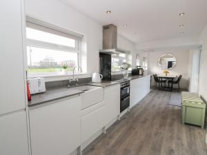 a kitchen with white cabinets and a large window at Marchdyke Farm Cottage in Lockerbie