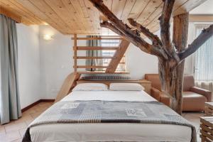 a bedroom with a large bed and a tree at Agriturismo Vento Alpino in Coredo