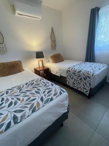a bedroom with two beds and a window with a lamp at Casa OM in El Cuyo