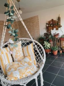 a swinging chair with pillows in a room with plants at Suite Bohème avec Jacuzzi in Sahoué