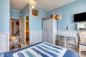 - une chambre avec des murs bleus, un lit et une télévision dans l'établissement Chambre d'hôtes - Le quartier haut, à Sète