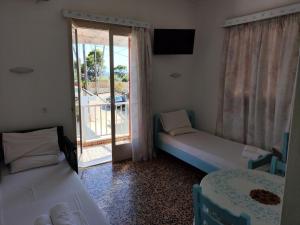 a room with two beds and a sliding glass door at Magdalini in Votsi