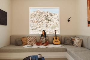 a woman sitting on a couch with a guitar at Bolder House By The Cohost Company in Joshua Tree