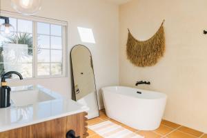 a bathroom with a white tub and a surfboard on the wall at Bolder House By The Cohost Company in Joshua Tree