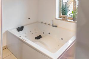 une baignoire blanche dans une salle de bains avec fenêtre dans l'établissement Fewo Mit Herz Und Holz Penzing, à Penzing 31 autres photos