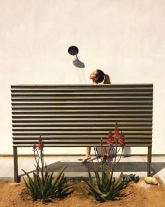 een vrouw zit met een waaier op een parkbankje bij Desert Bloom By The Cohost Company in Joshua Tree