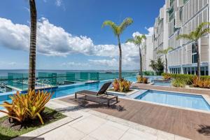 a swimming pool with palm trees and a building at Aconchegante apartamento em Cloc Marina Residence in Salvador