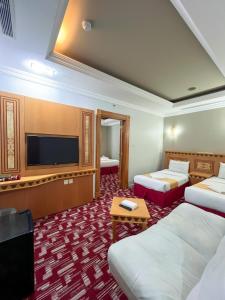una camera d'albergo con due letti e una TV a schermo piatto di فندق رهف مكة Rahaf Hotel Maka a Al Khansāk