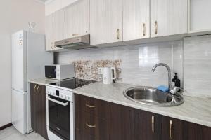 eine Küche mit Spüle und Kühlschrank in der Unterkunft Апартаменты в ЖК Ирина рядом с Баянтау in Pawlodar