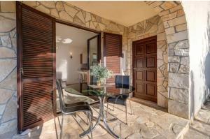 a glass table and chairs in front of a stone wall at Adrialana in Porozina