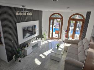 a living room with a couch and a flat screen tv at Villa exceptionnelle avec piscine privée et terrasse in Villamartin