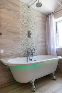 a bath tub in a bathroom with wooden walls at Achill Guest House in Solihull