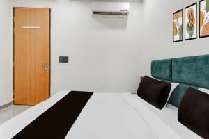 Un dormitorio con una cama blanca y una puerta de madera. en Hotel O Riwaz Inn, en Gwalior