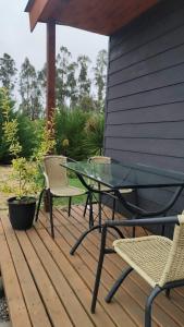 a glass table and chairs on a wooden deck at Cabaña Campestre in El Cerrillo +2 photos