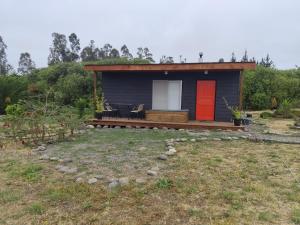 a small house with a red door on a yard at Cabaña Campestre in El Cerrillo