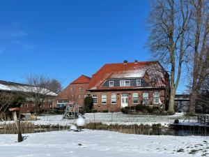 uma grande casa de tijolos com neve no chão em Landblick em Ovelgönne