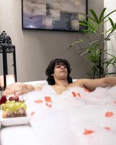 a man laying in a bath tub with a plate of food at Pousada Rosa Karioka in Praia do Rosa