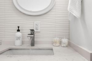 Un lavabo de baño con dispensador de jabón y un espejo. en Cozy By The Blue, en Miami 23 fotos más