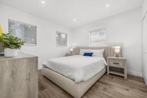 Un dormitorio blanco con una cama grande y dos ventanas. en Cozy By The Blue, en Miami