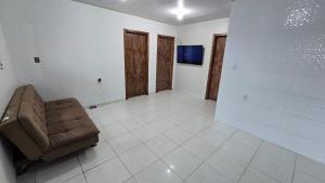 un soggiorno con un divano e una TV di Karina Saraiva a Palhoça