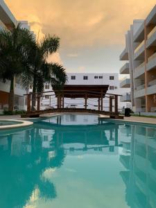 a swimming pool with a bench in front of a building at Sol & Arena Bayahibe Apartment in Bayahibe
