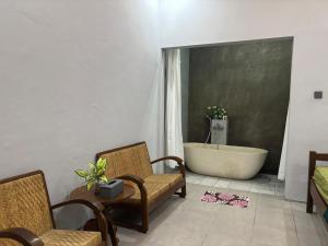 a bathroom with a bath tub and a chair and a bath tub at Omah Saha at Kraton in Yogyakarta