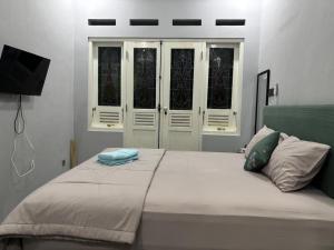 a bedroom with a large white bed with windows at Omah Saha at Kraton in Yogyakarta