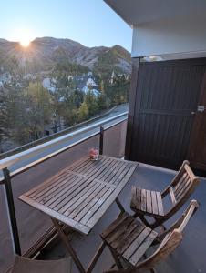 ein Holztisch und zwei Stühle auf einem Balkon in der Unterkunft centre Auron calme et montagne in Saint-Étienne-de-Tinée