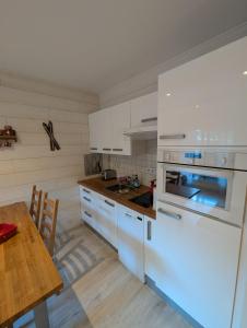 eine Küche mit weißen Geräten und einem Holztisch in der Unterkunft centre Auron calme et montagne in Saint-Étienne-de-Tinée