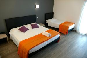 um quarto com 2 camas com lençóis laranja e branco em Hotel Désirée em San Benedetto del Tronto