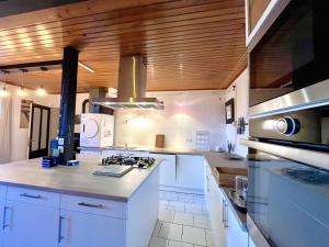 une cuisine avec des armoires blanches et un four à plaques de cuisson dans l'établissement Le Petit Four à Pain - Maison 4 personnes à la Campagne, à Neuvicq-Montguyon