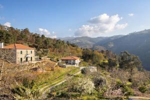ein Haus auf einem Hügel mit Bergen im Hintergrund in der Unterkunft Quintinha De Pinouco in Miomães