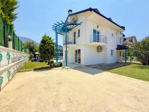 una casa bianca con una recinzione e una strada sterrata di Villa Fergana a Ovacik