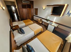 a small room with two beds and a desk at Hotel Santoni in Guarapuava