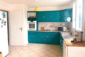 a green kitchen with blue cabinets and a sink at Maison le 21B au coeur de Lesconil in Plobannalec-Lesconil
