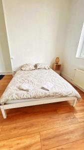 a white bed in a room with a wooden floor at Maison partagée 4 chambres Saint Roch Roubaix in Roubaix