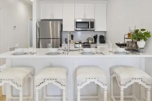 a kitchen with a white counter with two stools at Weekend Escape on the Coast-Relax & Unwind in Pass Christian