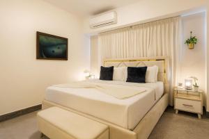 a white bedroom with a large white bed and a stool at Upscale City Center Condo, Pool, Gym in Santo Domingo +55 photos