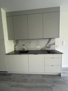 a kitchen with white cabinets and a sink at Sea and lake apartament in Mielno