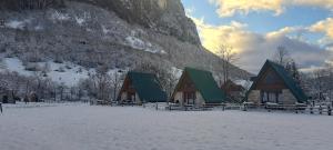 eine Gruppe von Gebäuden im Schnee mit einem Berg in der Unterkunft Eco resort Komarnica in Šavnik