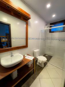 une salle de bain avec un lavabo et des toilettes dans l'établissement Pousada Kauai, à Imbituba
