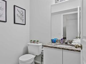 a white bathroom with a toilet and a sink at Rockies 3BR Townhome w Stunning Views Near DT in Canmore +5 photos