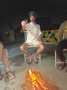 a man sitting on a chair next to a fire at The Pink Nest - Backpackers Abode in Jaipur